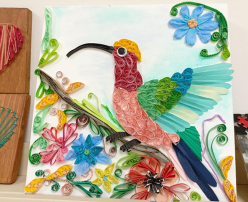 Zdjęcie_nr_1_przedstawia_kolorowego_kolibra_wykonanego_metodą_quillingu_podczas_zajęć_i_arteterapii.png