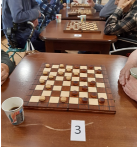Zdjęcie_nr_4_przedstawia_rozłożone_stanowiska_i_grających_w_warcaby_uczestników_turnieju.png