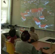 Zdjęcie_nr_5_przedstawia_uczestników_wykładów_oglądających_zdjęcia_z_projektora.png