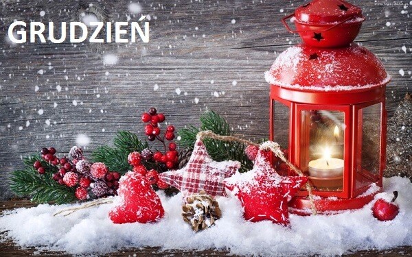 Świąteczna grudniowa kartka. Na białym śniegu leżą dekoracje: materiałowe gwiazdki, czerwone serduszko, zielone gałązki, szyszka, jabłko oraz czerwona latarenka we wnętrzu której płonie świeczka.