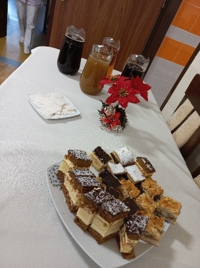 Zdjęcie. Przedstawia stół a na nim talerz z ciastami, opłatkiem oraz napoje.