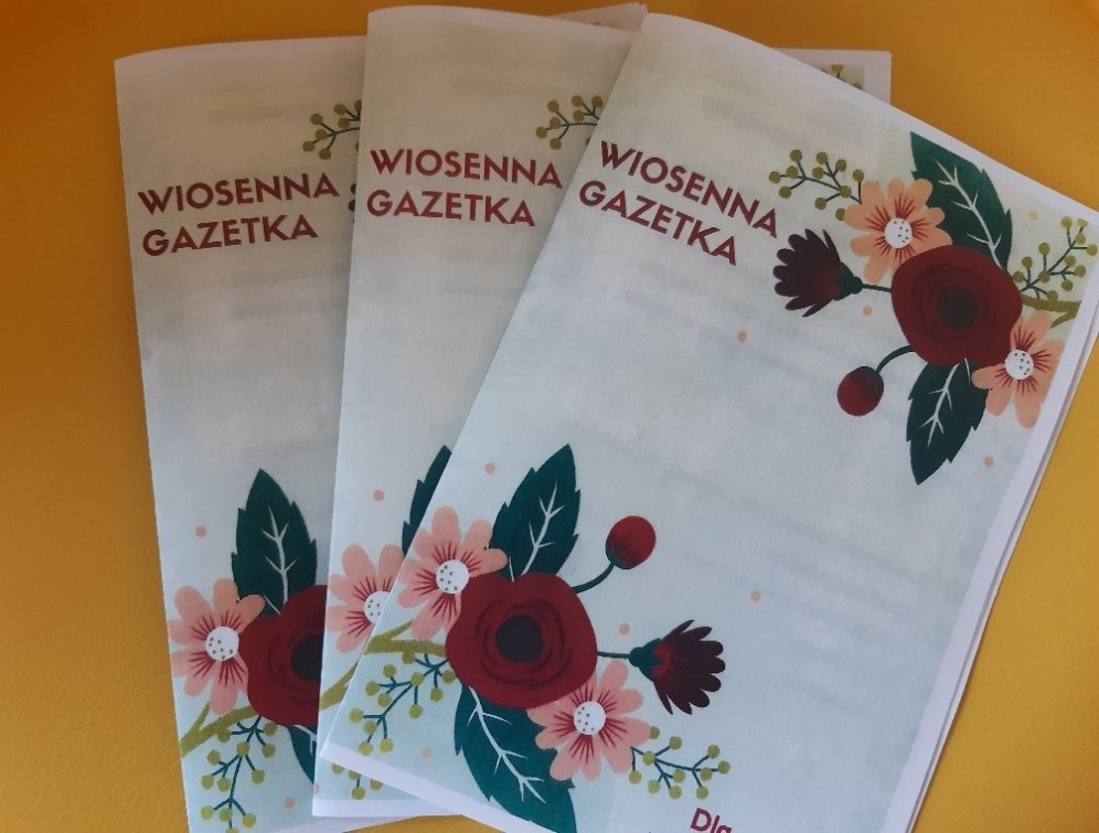 Wiosenna gazetka. Na białym papierze nadruk kolorowego bukietu kwiatów z napisem Wiosenna Gazetka