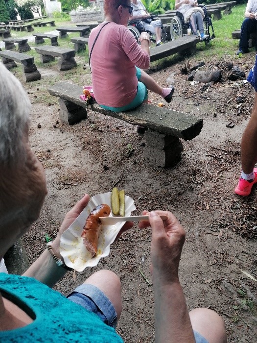Mieszkanka degustuje zgrillowaną kiełbaskę z ogórkiem konserwowym
