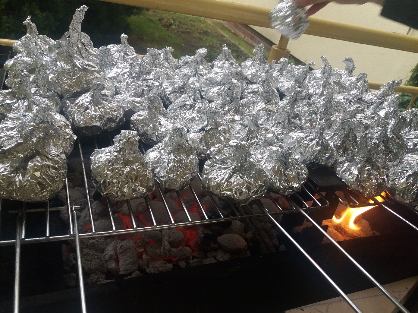 Na zdjęciu widać ziemniaki zawinięte w folię położone na grillu.